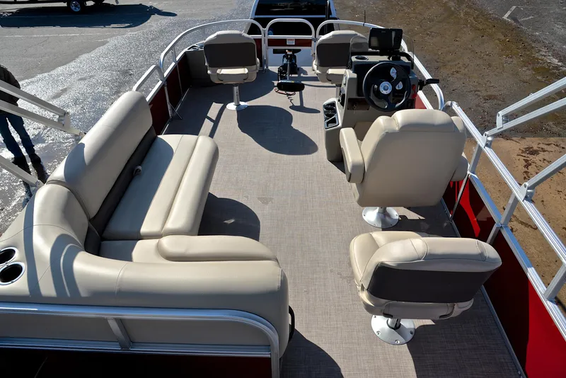 Slide: The Image of 2024 Sun Tracker BASS BUGGY 18 pontoon boat interior with beige seating and steering console. - 18