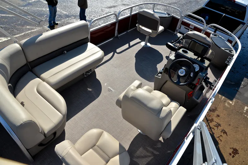 Slide: The Image of 2024 Sun Tracker BASS BUGGY 18 pontoon boat interior with beige seating and steering console. - 19