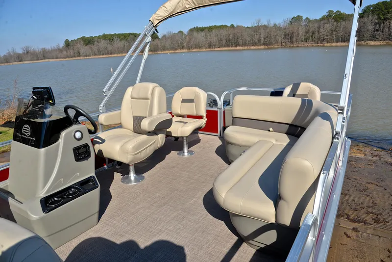 Slide: The Image of 2024 Sun Tracker BASS BUGGY 18 pontoon boat with beige seating on a calm lake. - 23