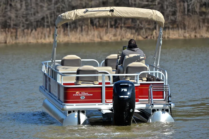 Slide: The Image of 2024 Sun Tracker BASS BUGGY 18 pontoon boat on a lake, rear view. - 7
