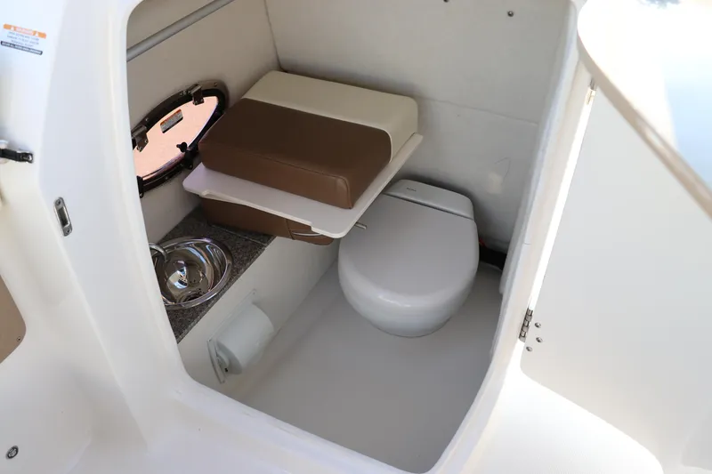 Slide: The Image of 2018 Chaparral 230 Suncoast boat interior with compact toilet and sink. - 13