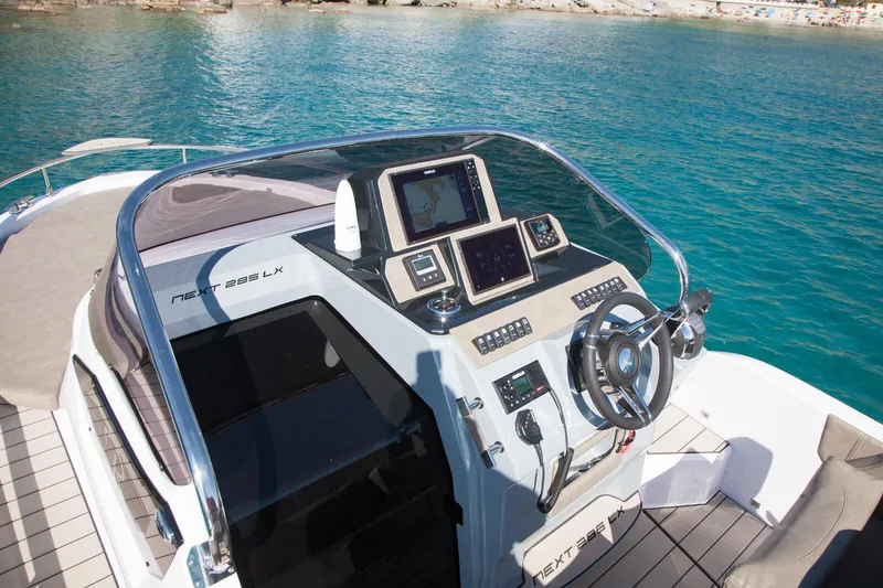 Slide: The Image of 2025 Ranieri NEXT 285 XL boat dashboard with modern navigation equipment on clear blue water. - 26