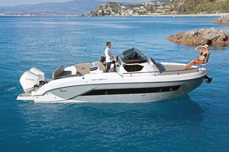 Slide: The Image of 2025 Ranieri NEXT 285 XL boat cruising in clear blue waters near rocky coastline. - 6