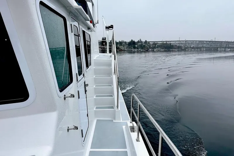 Slide: The Image of 2025 Helmsman Trawlers 46 Pilothouse cruising on calm waters, side view. - 8