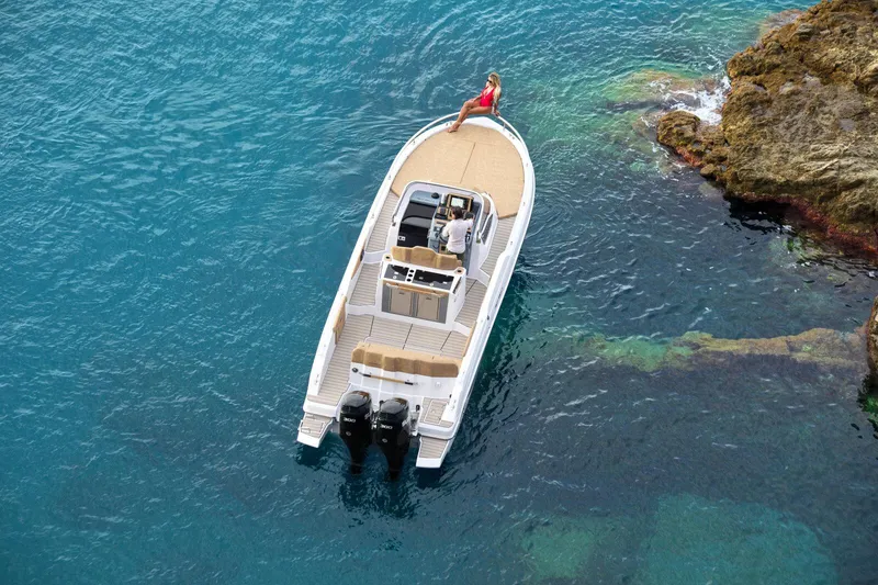 Slide: The Image of 2025 Ranieri NEXT 330 XL boat near rocky shoreline in clear blue water. - 3