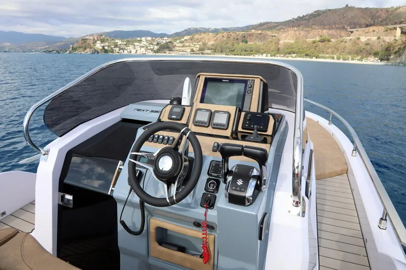 Slide: The Image of 2025 Ranieri NEXT 330 XL boat cockpit with modern controls and scenic coastal view. - 8