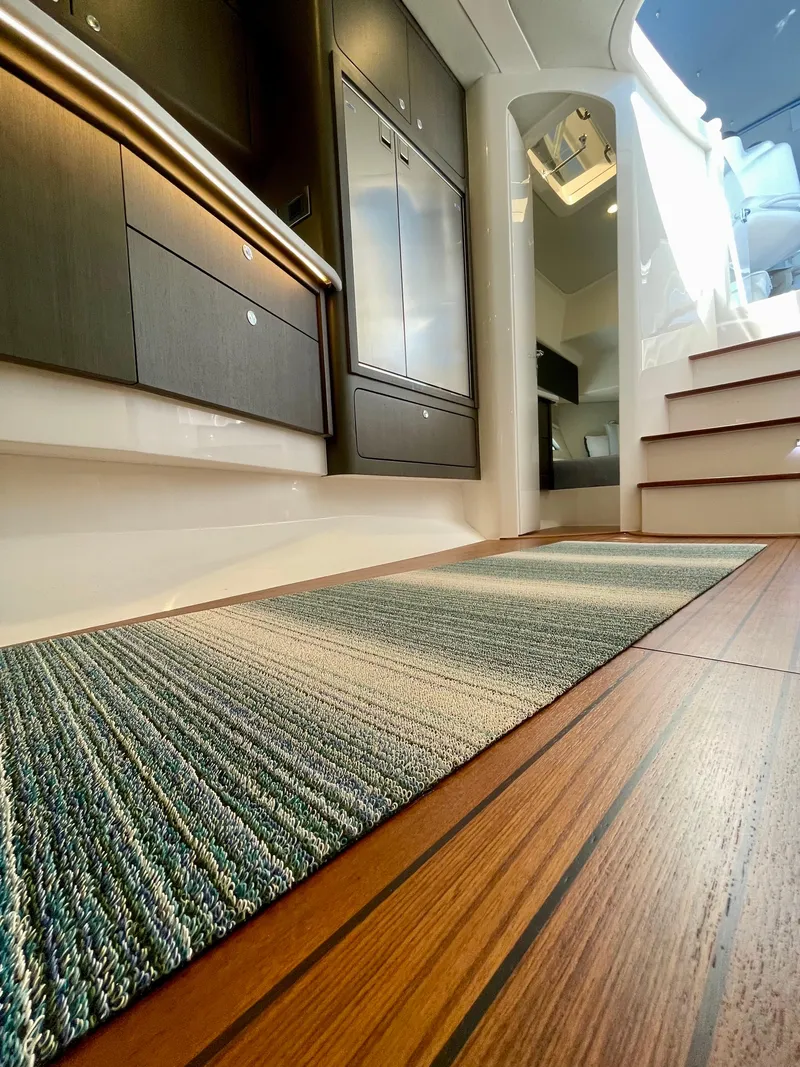 Slide: The Image of Interior of 2022 Intrepid 477 Evolution yacht, featuring wood flooring and modern cabinetry. - 15