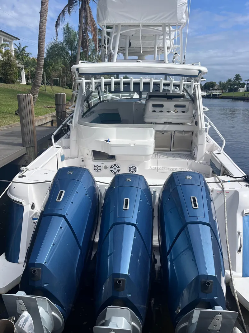 Slide: The Image of 2022 Intrepid 477 Evolution boat with triple blue outboard engines docked by a waterfront. - 4