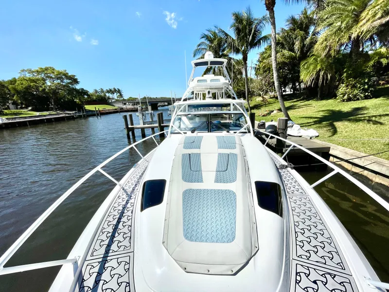 Slide: The Image of 2022 Intrepid 477 Evolution yacht docked by palm trees, showcasing sleek design and spacious deck. - 5
