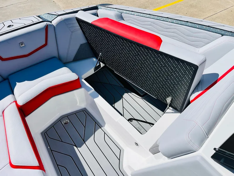 Slide: The Image of 2025 Nautique Super Air Nautique G23 interior with open storage compartment, red and gray seating. - 18