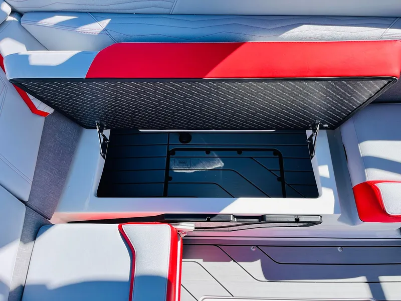 Slide: The Image of 2025 Nautique Super Air Nautique G23 storage compartment with red and gray seating. - 31