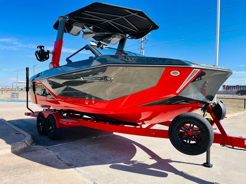 Slide: The Image of 2025 Nautique Super Air Nautique G23 boat, red and gray, on trailer, sunny day. - 4