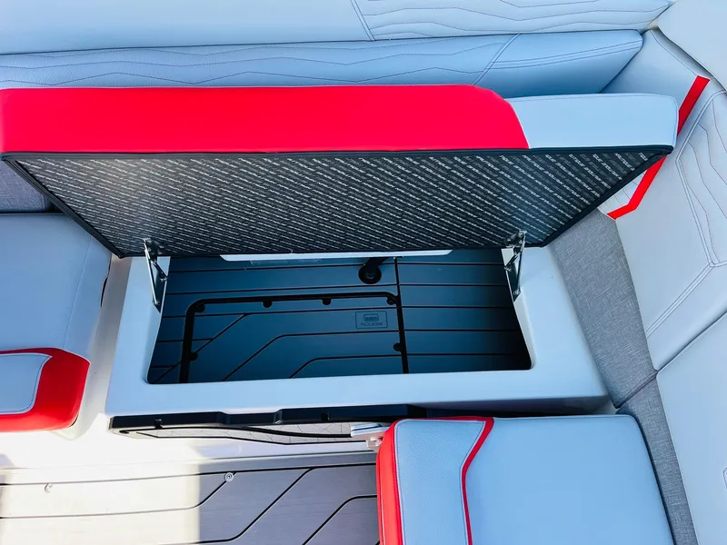 Slide: The Image of 2025 Nautique Super Air Nautique G23 storage compartment with red and gray seating. - 41