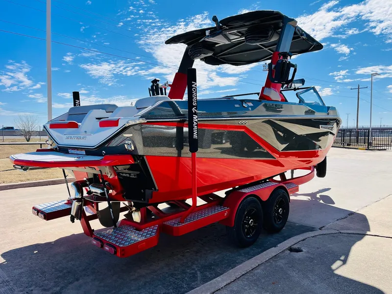 Slide: The Image of 2025 Nautique Super Air Nautique G23 boat on trailer, red and black design, sunny day. - 6