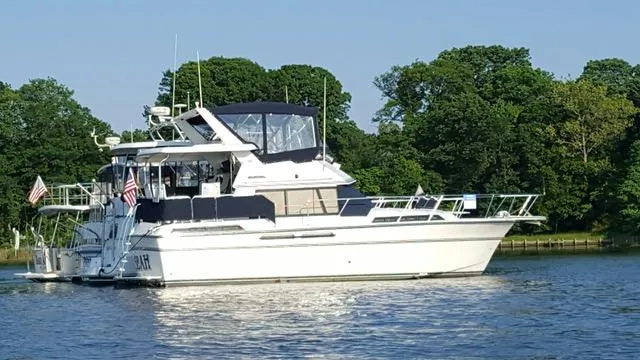 Slide: The Image of 1988 President 37 Sundeck yacht on calm water, surrounded by lush greenery. - 3