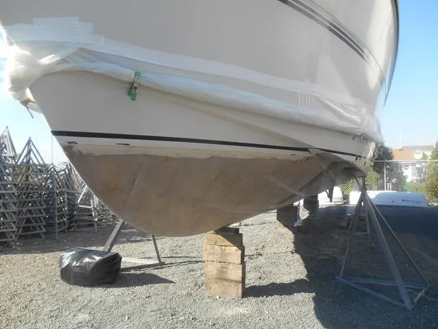 Slide: The Image of 1988 President 37 Sundeck boat on stands, undergoing maintenance, with visible hull and protective covering. - 62