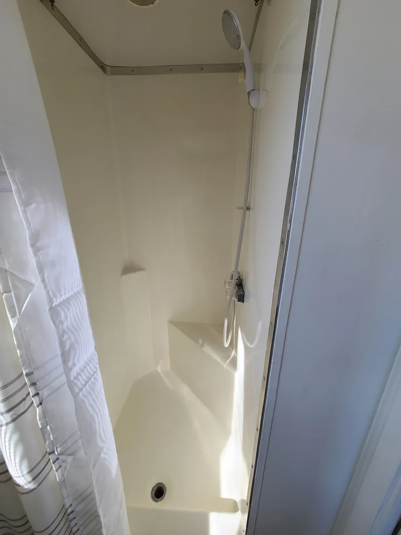 Slide: The Image of Compact shower area in a 1993 Gibson SPORT SERIES boat, featuring a white curtain and handheld showerhead. - 18