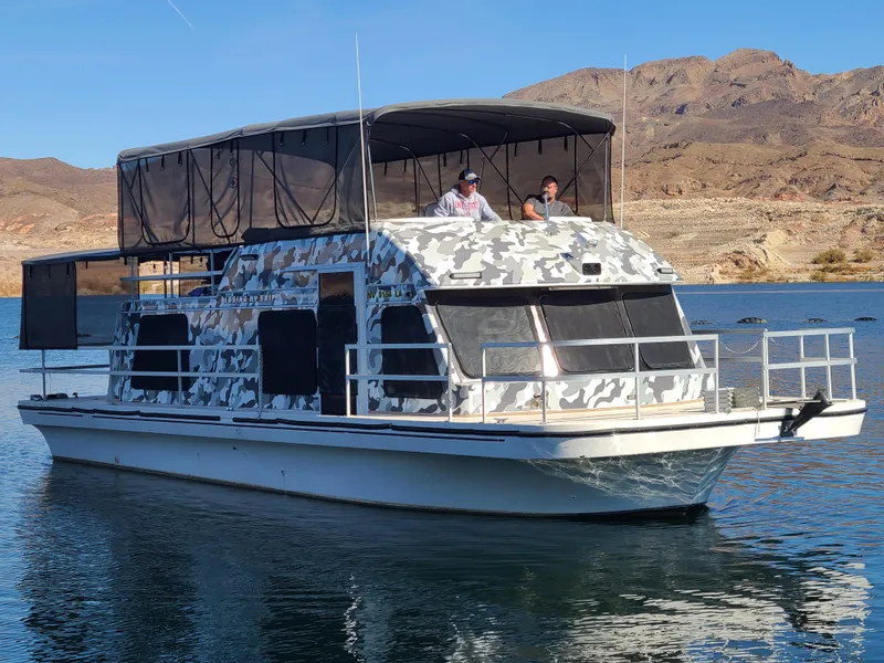 Slide: The Image of Camouflage-patterned 1993 Gibson SPORT SERIES boat on a lake with rocky hills in the background. - 6