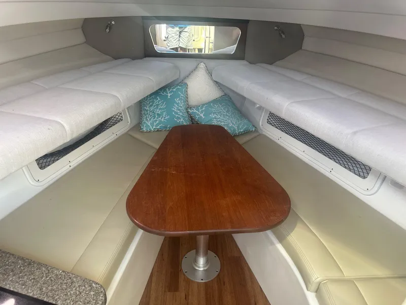 Slide: The Image of 2018 Robalo R305 Walkaround cabin interior with seating and wooden table. - 11