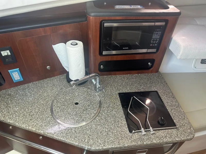 Slide: The Image of 2018 Robalo R305 Walkaround boat kitchen with sink, stove, and microwave. - 12