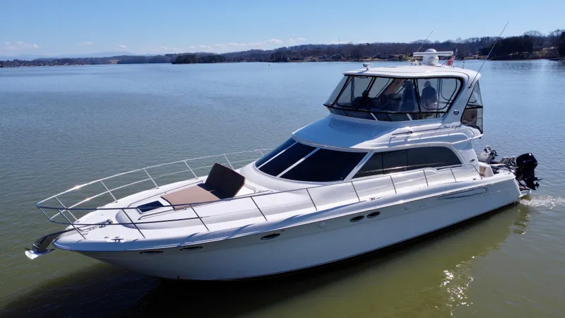 Slide: The Image of 2001 Sea Ray 480 Sedan Bridge cruising on a calm lake under clear blue skies. - 1
