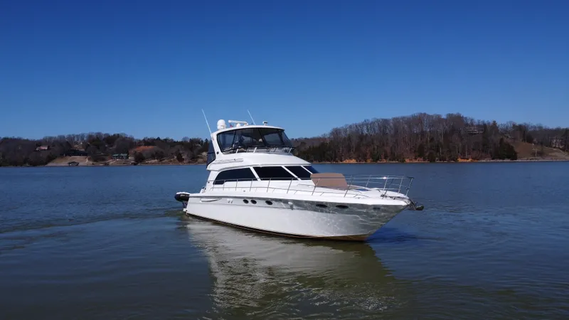 Slide: The Image of 2001 Sea Ray 480 Sedan Bridge yacht cruising on a calm lake under clear blue skies. - 10
