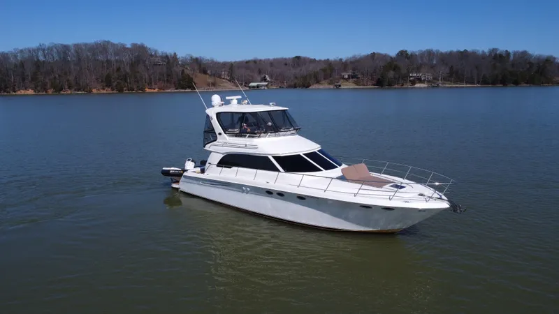 Slide: The Image of 2001 Sea Ray 480 Sedan Bridge yacht on a calm lake with wooded shoreline. - 11