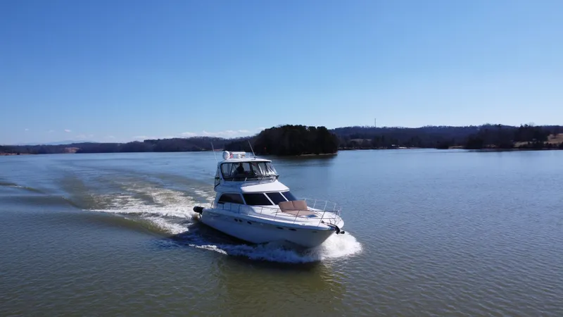 Slide: The Image of 2001 Sea Ray 480 Sedan Bridge cruising on a serene lake under clear blue skies. - 12