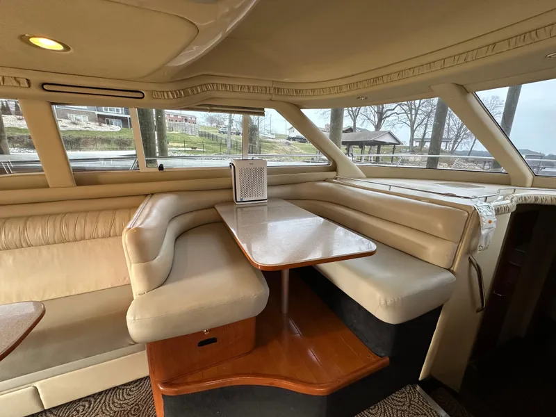 Slide: The Image of Interior of 2001 Sea Ray 480 Sedan Bridge with beige seating and wooden table. - 15