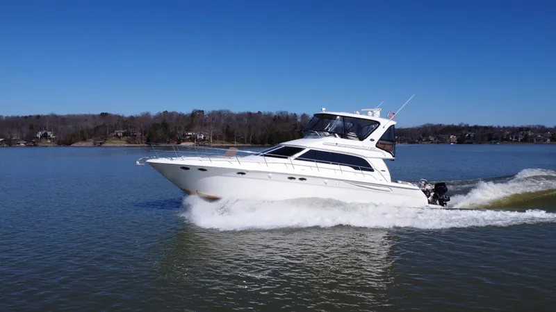 Slide: The Image of 2001 Sea Ray 480 Sedan Bridge cruising on a calm lake under clear blue skies. - 2