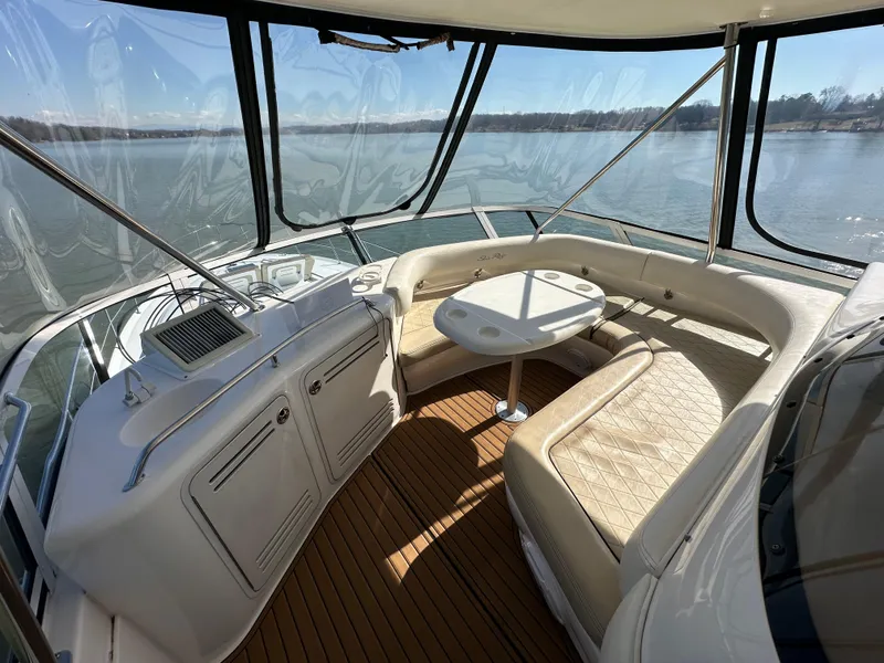 Slide: The Image of 2001 Sea Ray 480 Sedan Bridge interior with seating and table, overlooking water. - 24
