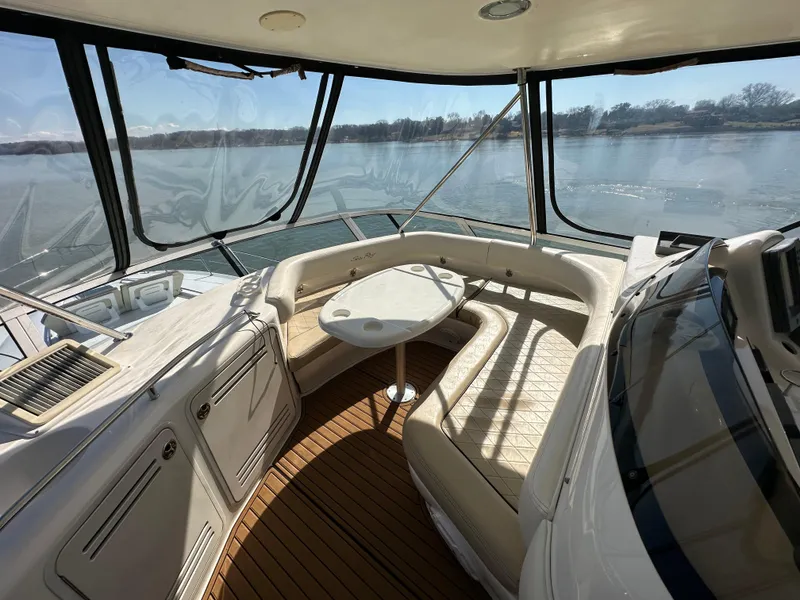 Slide: The Image of 2001 Sea Ray 480 Sedan Bridge interior with seating and table, overlooking serene water. - 25