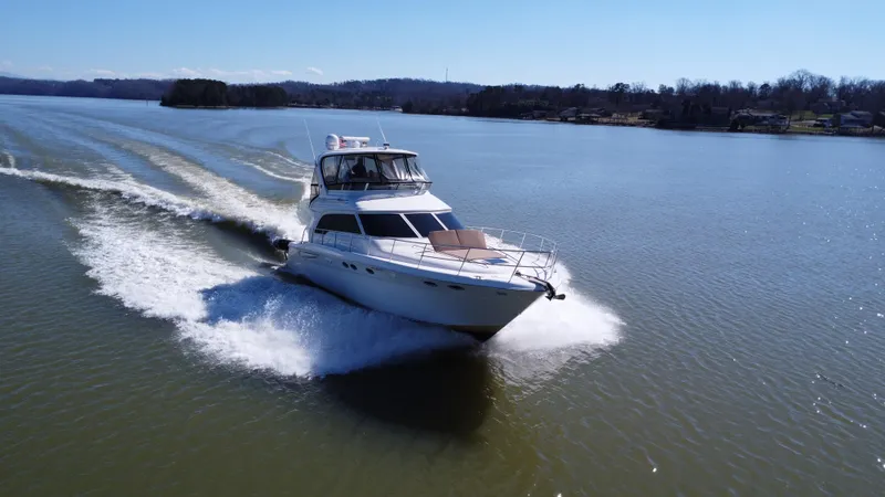 Slide: The Image of 2001 Sea Ray 480 Sedan Bridge cruising on a serene lake under clear skies. - 5
