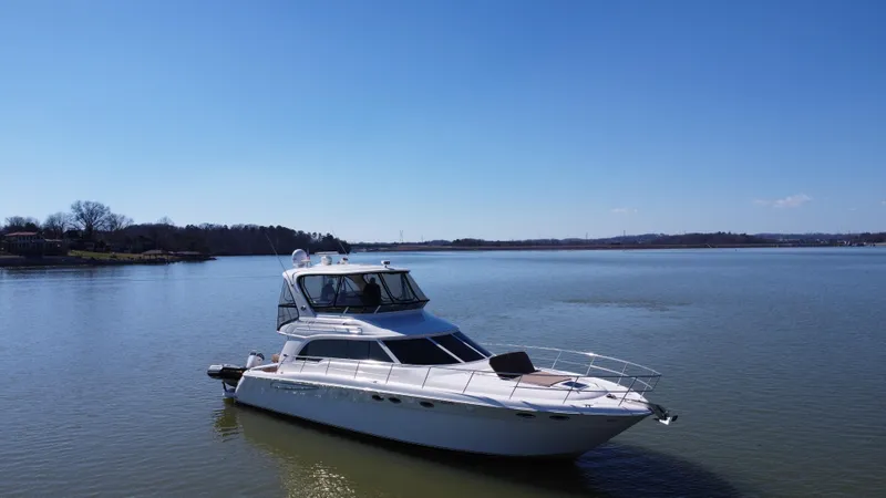 Slide: The Image of 2001 Sea Ray 480 Sedan Bridge yacht on calm lake under clear blue sky. - 6