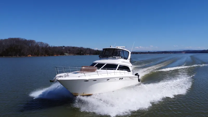Slide: The Image of 2001 Sea Ray 480 Sedan Bridge cruising on a calm lake under clear blue skies. - 7