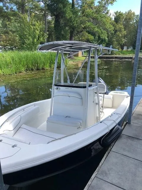 Slide: The Image of 2014 NauticStar 1900 XS boat docked by a lush, green shoreline. - 21