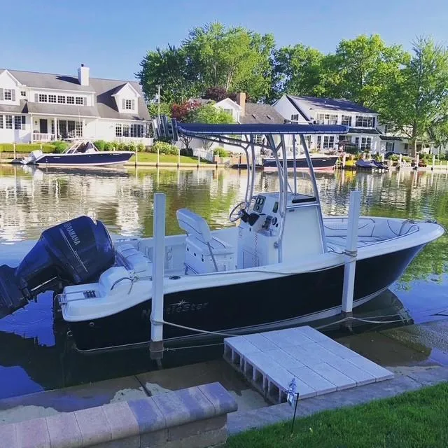 Slide: The Image of 2014 NauticStar 1900 XS boat docked by waterfront homes, serene setting. - 7