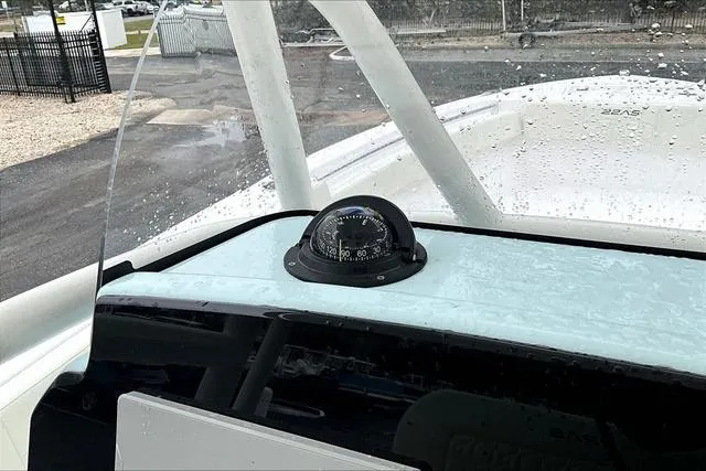 Slide: The Image of 2025 Aquasport 2200 Center Console boat with compass on dashboard, wet from rain. - 27