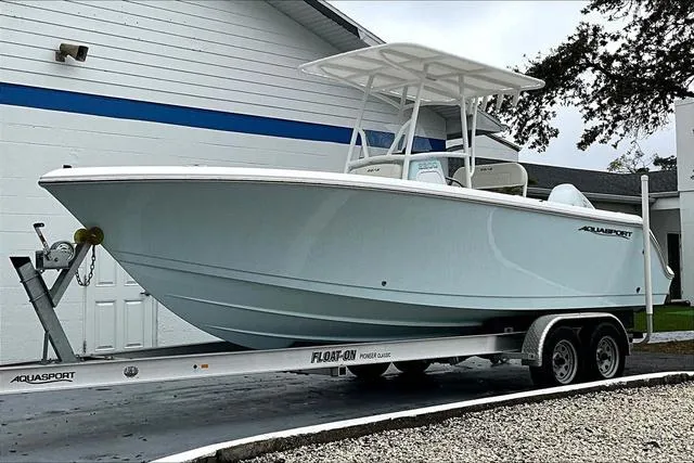 Slide: The Image of 2025 Aquasport 2200 Center Console boat on trailer, parked outdoors. - 31