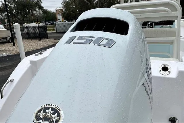 Slide: The Image of 2025 Aquasport 2200 Center Console boat engine with "150" marking, wet with raindrops. - 8
