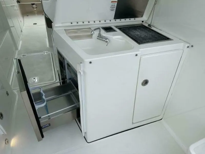 Slide: The Image of 2019 Pursuit DC 325 Dual Console boat kitchenette with sink, grill, and storage drawers. - 21