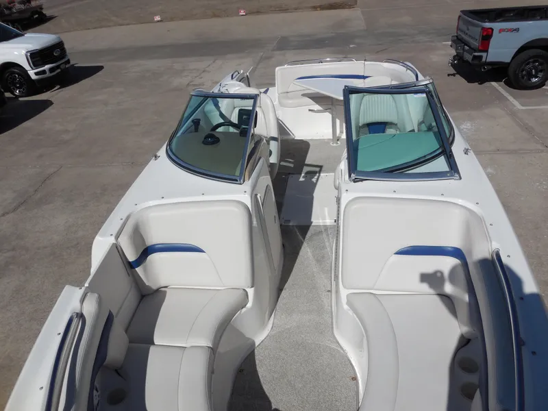 Slide: The Image of 2003 Chaparral Sunesta 243 boat interior with white and blue seating, parked on concrete. - 11