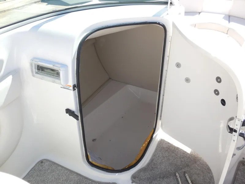 Slide: The Image of 2003 Chaparral Sunesta 243 boat storage compartment with open door, white interior, and carpeted floor. - 14