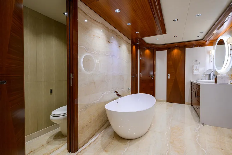 Slide: The Image of Luxurious bathroom on 2020 Westport Motor Yacht with freestanding tub and elegant wood accents. - 14