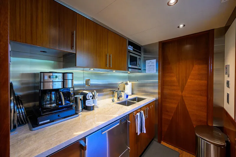 Slide: The Image of Modern kitchen in a 2020 Westport Motor Yacht with wood cabinetry and stainless steel appliances. - 16