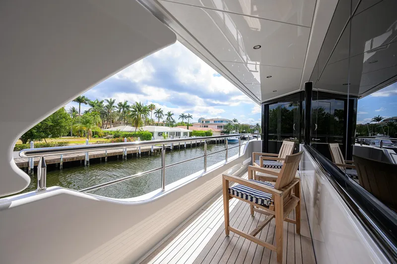 Slide: The Image of Luxurious 2020 Westport Motor Yacht deck with wooden chairs, overlooking serene waterfront. - 43