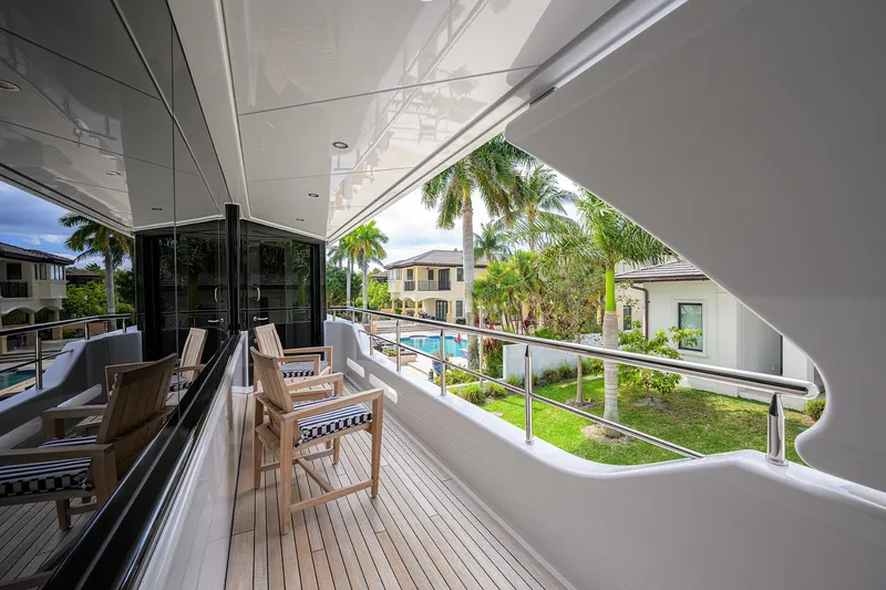 Slide: The Image of Luxurious 2020 Westport Motor Yacht deck with wooden chairs, overlooking tropical scenery. - 44