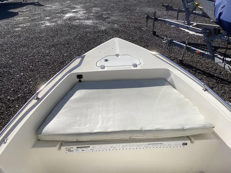 Slide: The Image of 2002 Key West 1720 boat bow with cushioned seating and storage hatch. - 14