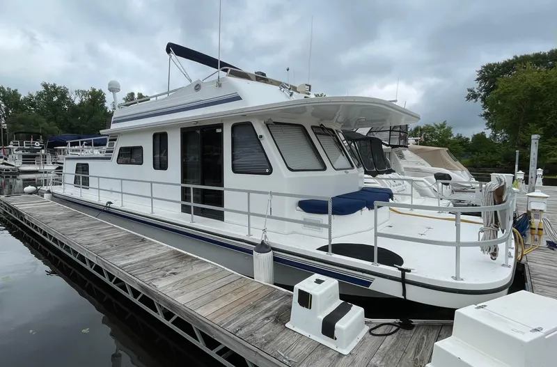 Slide: The Image of 2003 Gibson 50 Classic houseboat docked at marina under cloudy sky. - 0