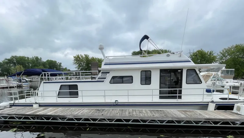 Slide: The Image of 2003 Gibson 50 Classic houseboat docked at a marina under cloudy skies. - 1